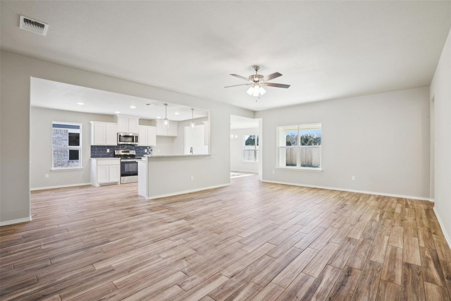 Unfurnished living room with ceiling fan, light wood finished floors, healthy amount of natural light, and recessed lighting