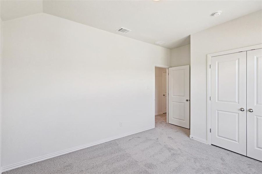 Unfurnished bedroom featuring lofted ceiling, light colored carpet, and a closet