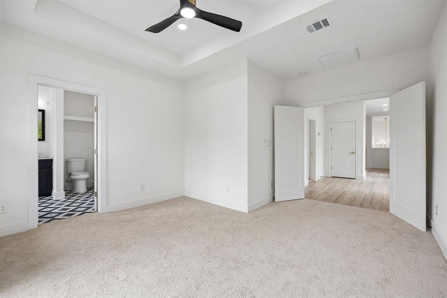 Carpeted room with a tray ceiling and contemporary black ceiling fan Carpeted room with a tray ceiling and contemporary black ceiling fan