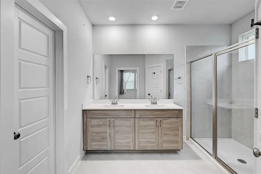 Bathroom with double vanity, a stall shower, and tile patterned floors Bathroom with double vanity, a stall shower, and tile patterned floors