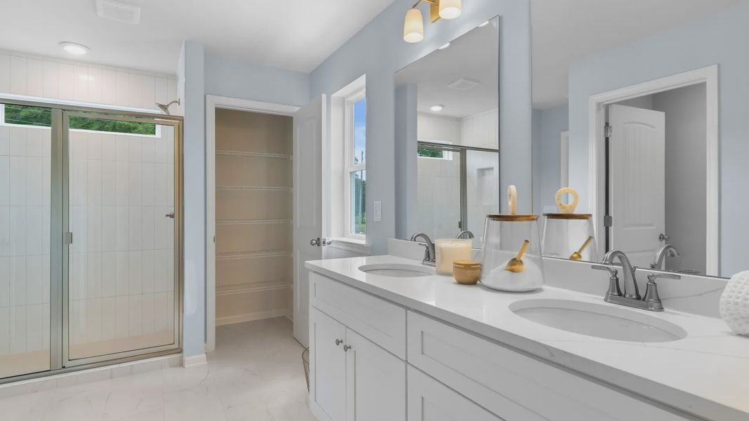 Bathroom with double vanities, quartz countertops, modern fixtures, and large mirror in new construction townhome.