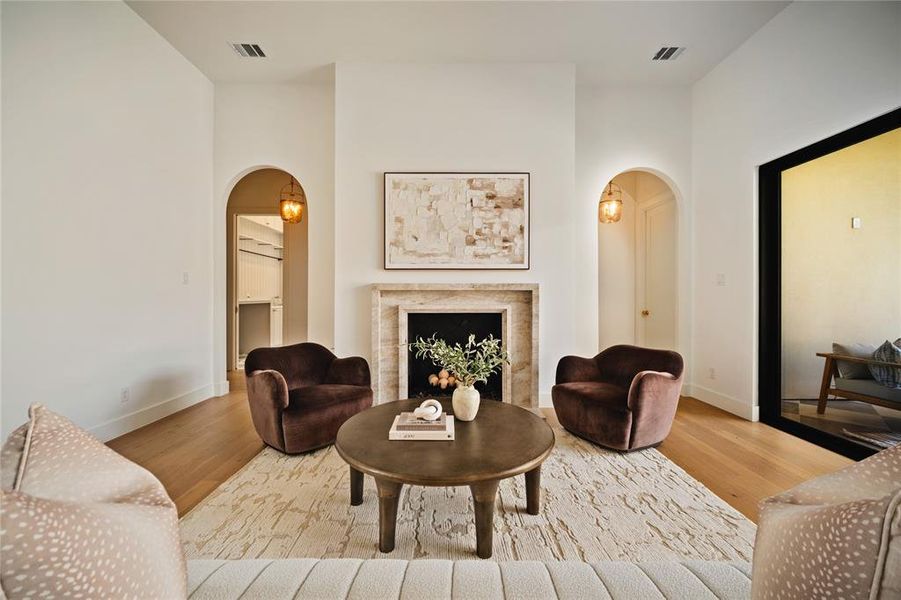 Living area featuring arched walkways, wood finished floors, and a high end fireplace
