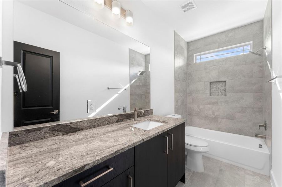 Full bathroom featuring tile patterned flooring, vanity, toilet, and tiled shower / bath