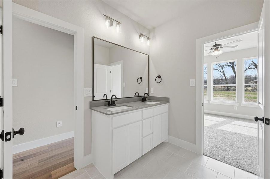 Full bath featuring double vanity, ceiling fan, light tile patterned floors, and light carpet