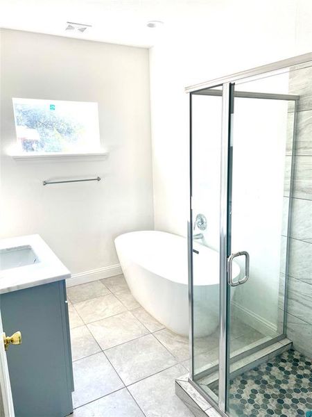 Bathroom featuring tile patterned flooring, shower with separate bathtub, and vanity