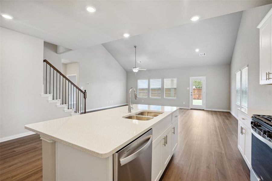 Kitchen featuring white cabinetry, an island with sink, stainless steel appliances, hardwood / wood-style flooring, and sink