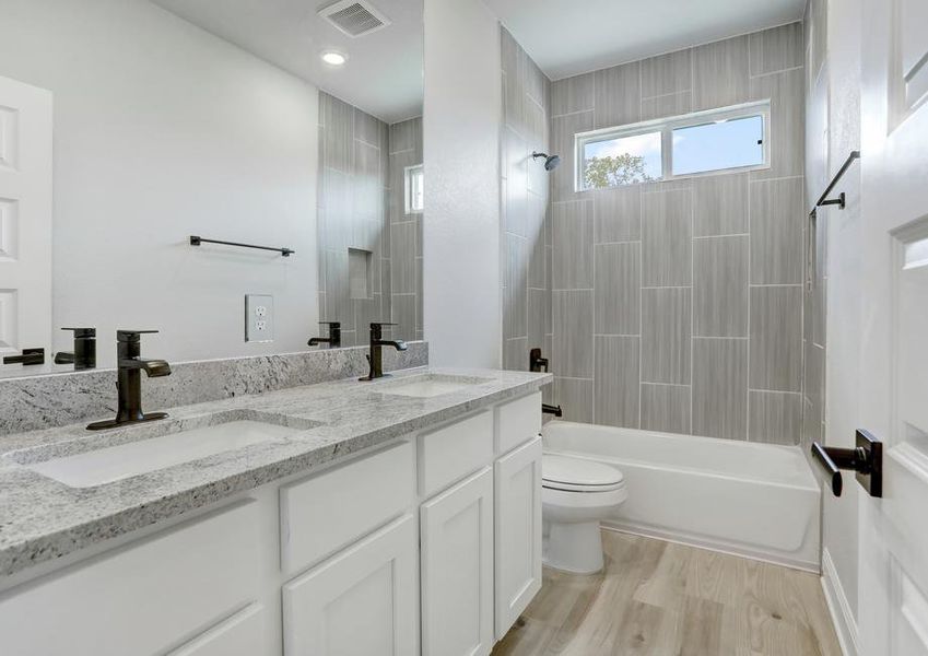 Guest bathroom with dual shower and tub, white cabinets, and granite countertops.