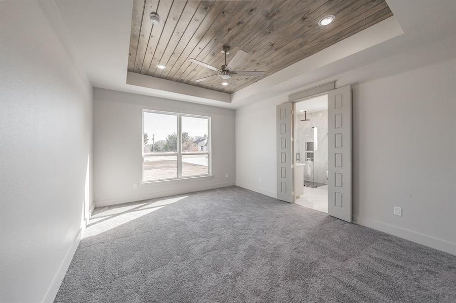 Carpeted empty room featuring wooden ceiling, a tray ceiling, a ceiling fan, and recessed lighting