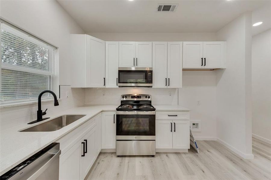 Kitchen featuring white cabinets, light hardwood / wood-style flooring, stainless steel appliances, and sink