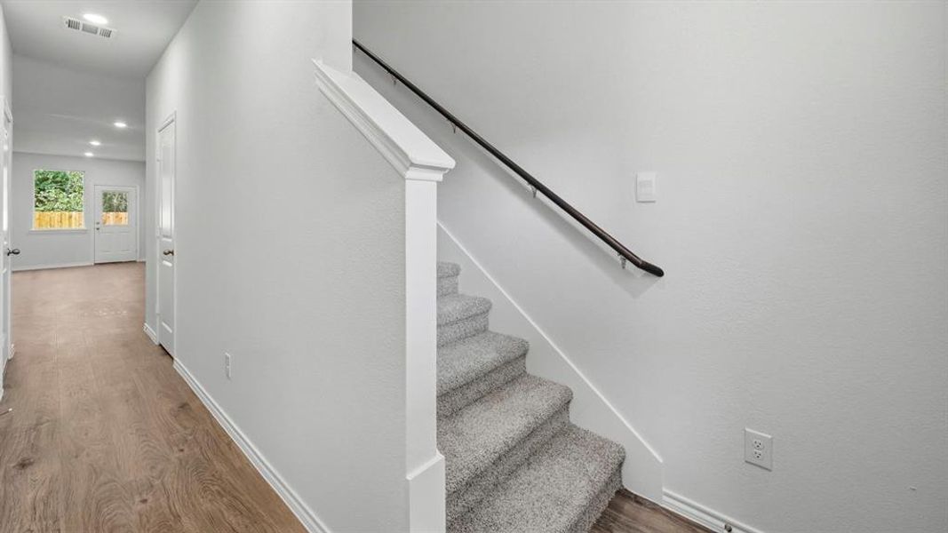 Stairs with wood finished floors and recessed lighting