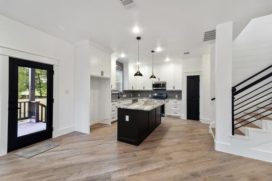 Spacious kitchen with custom cabinetry, a must-have island with pendant lights and black accents throughout.