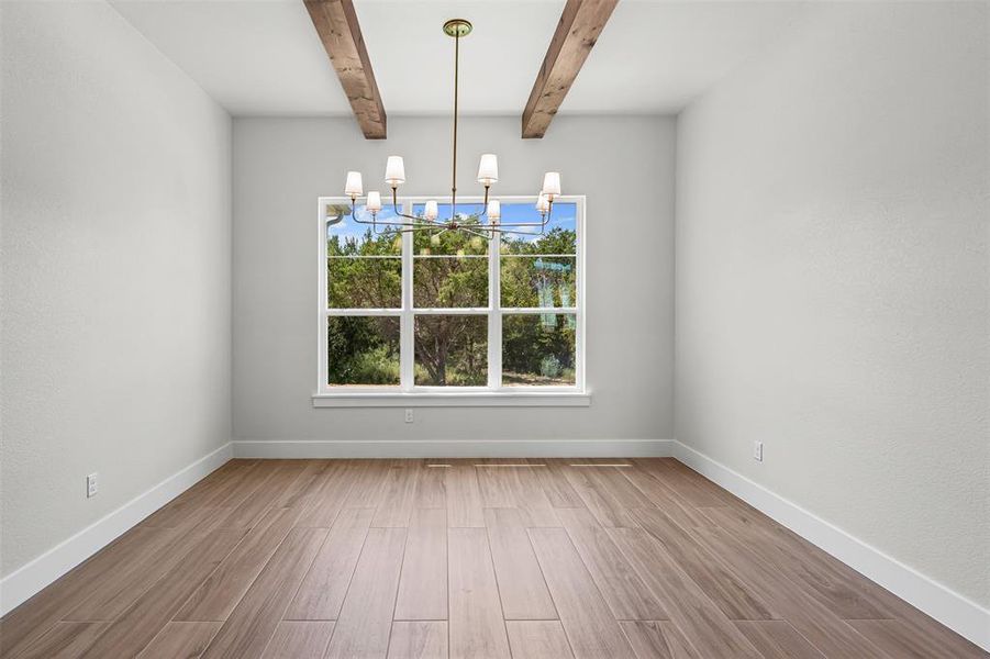 Unfurnished dining area featuring light wood finished floors, a chandelier, and beam ceiling Unfurnished dining area featuring light wood finished floors, a chandelier, and beam ceiling