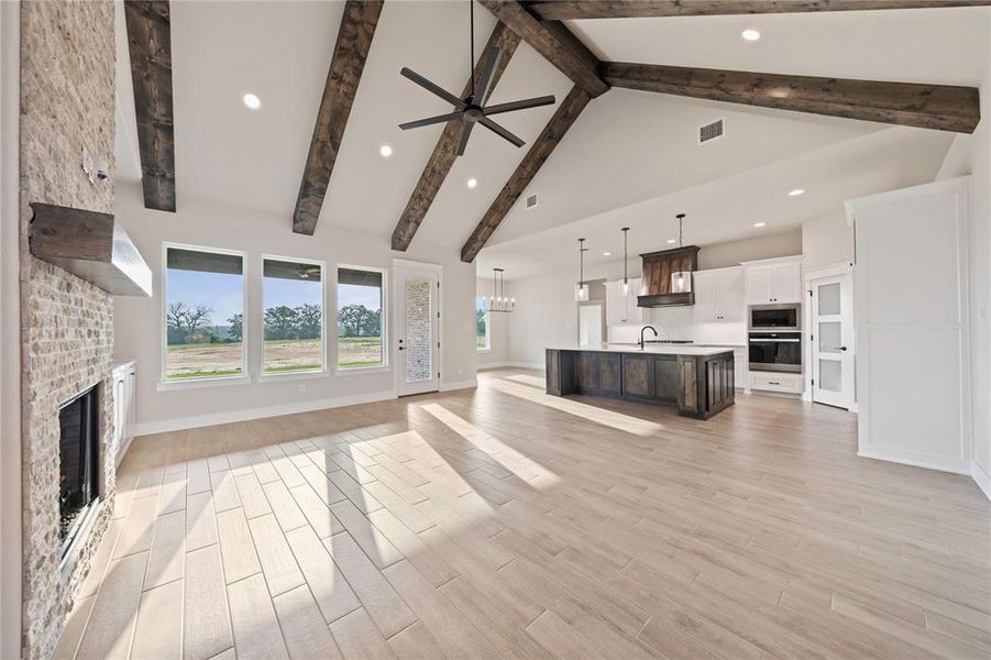 Unfurnished living room with a fireplace, beamed ceiling, high vaulted ceiling, a ceiling fan, and recessed lighting Unfurnished living room with a fireplace, beamed ceiling, high vaulted ceiling, a ceiling fan, and recessed lighting