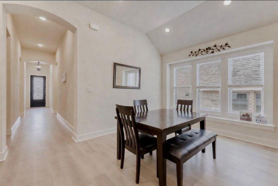 Dining room featuring arched walkways, lofted ceiling, light wood-style floors, and recessed lighting