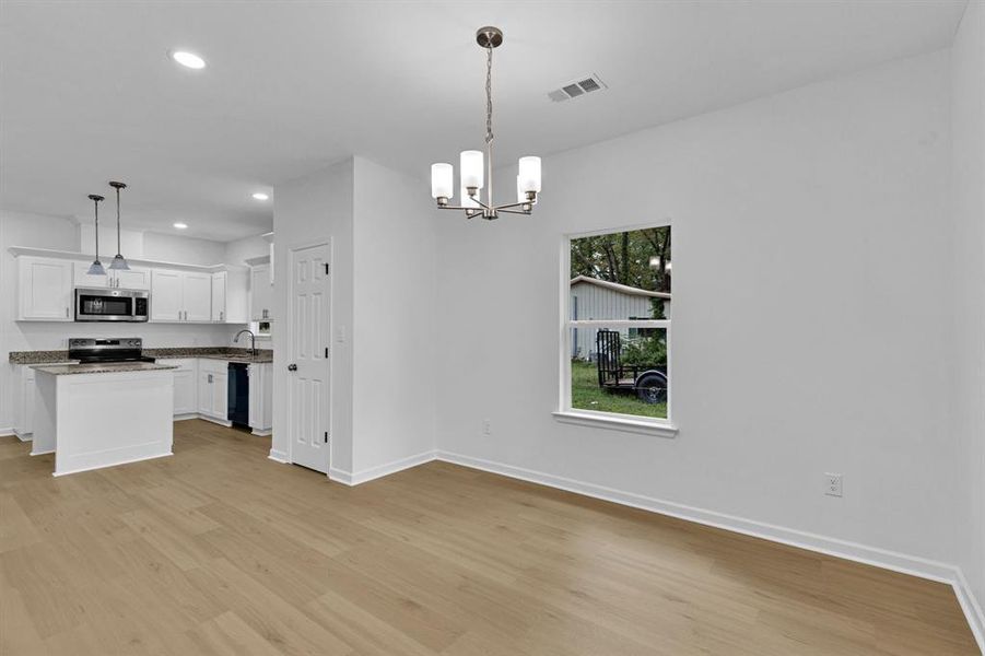 Kitchen featuring recessed lighting, white cabinetry, light wood-style floors, and hanging light fixtures Kitchen featuring recessed lighting, white cabinetry, light wood-style floors, and hanging light fixtures