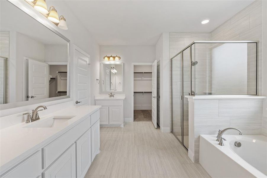 Bathroom with a spacious closet, a garden tub, two vanities, a shower stall, and recessed lighting