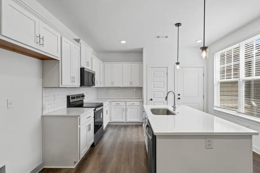 Kitchen featuring white shaker-style cabinetry, a subway tile backsplash, and dark wood-finish flooring