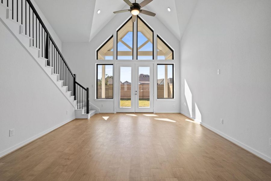 A vaulted ceiling soars overhead, filling the space with light and a sense of grandeur. Below, elegant double doors frame the entryway, drawing the eye upward and enhancing the open, airy feel of the room.