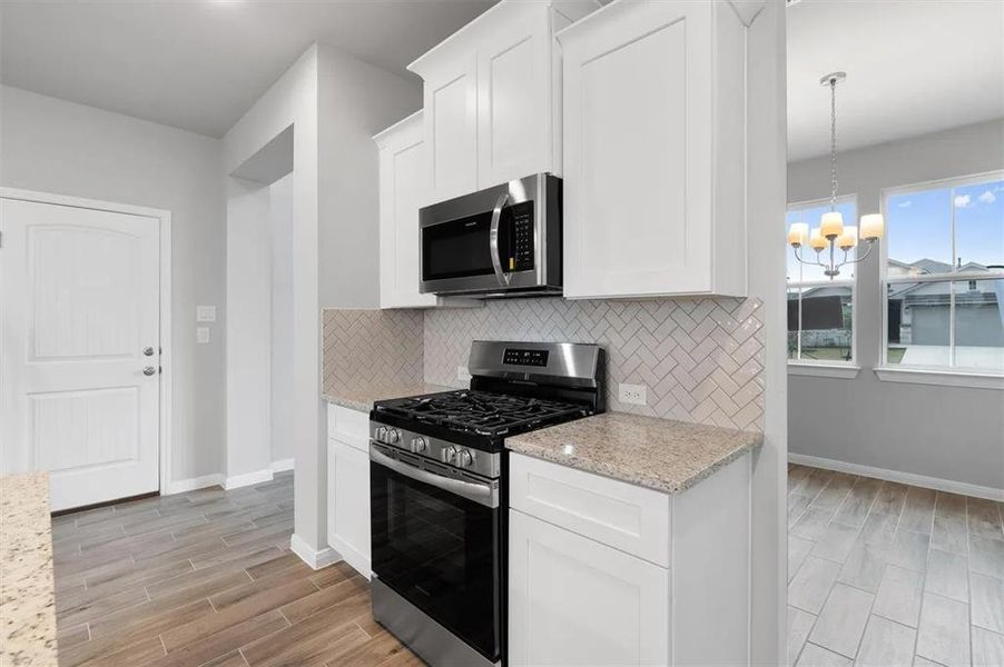 A contemporary kitchen space boasts stainless steel appliances, white cabinetry, and durable tile flooring.