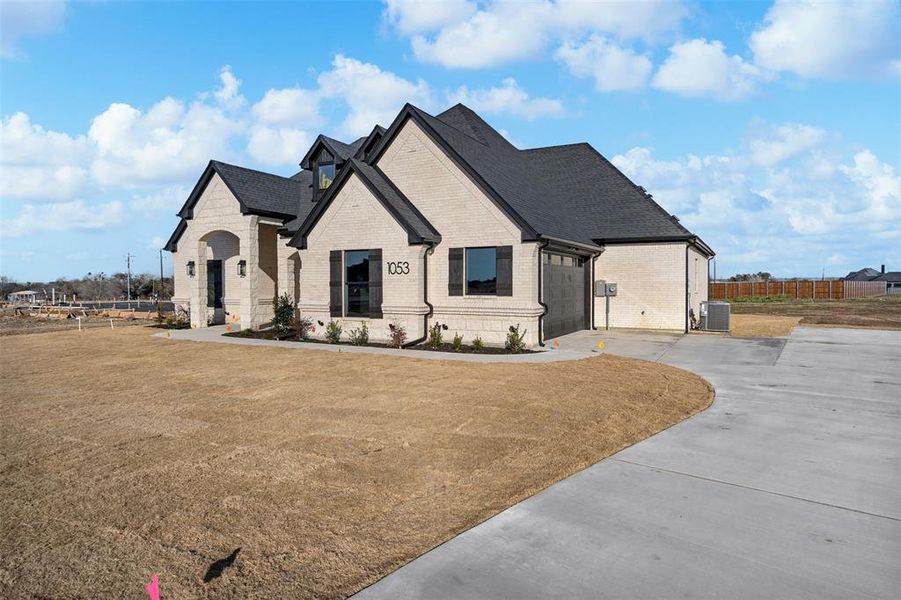 French country style house with a garage, central AC, and a front lawn