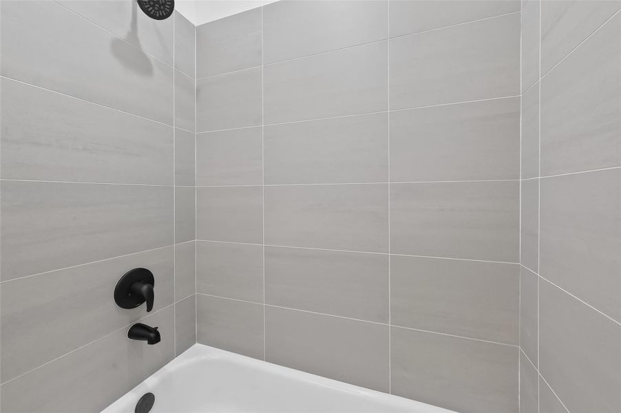 This bathroom features a modern shower with sleek gray tiles and matte black fixtures, offering a clean and contemporary look.