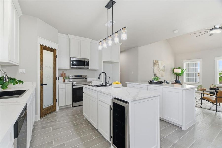 Kitchen featuring a center island with sink, pendant lighting, open floor plan, beverage cooler, and stainless steel appliances