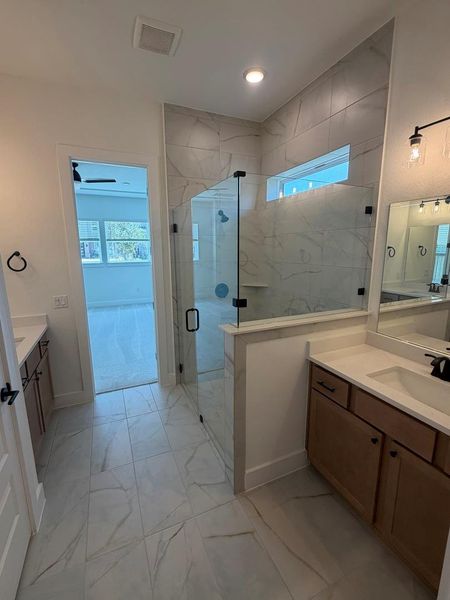 Luxurious primary bath with dual vanities and an expansive glass-enclosed shower. Luxurious primary bath with dual vanities and an expansive glass-enclosed shower.