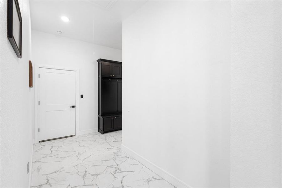 Hall featuring light marble finish floors, attic access, and recessed lighting