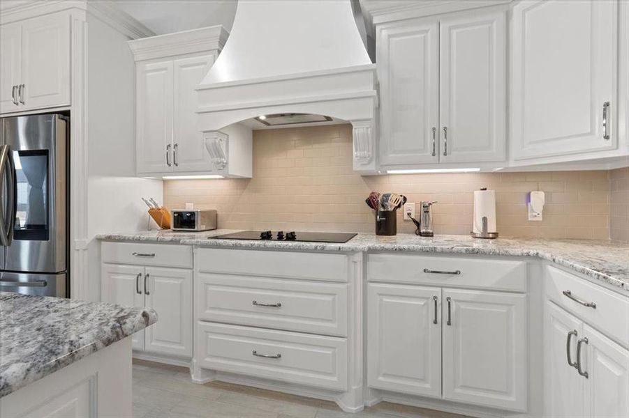 Kitchen featuring white cabinets, decorative backsplash, custom exhaust hood, black electric cooktop, and smart refrigerator