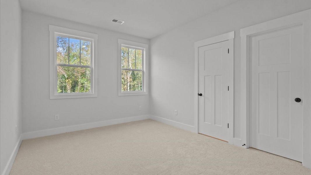 Elegant bedroom retreat featuring soft carpet and oversized windows that create a bright, welcoming space
