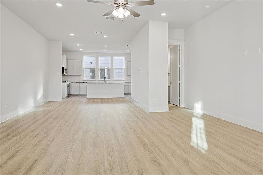 Unfurnished living room featuring baseboards, ceiling fan, and light wood finished floors