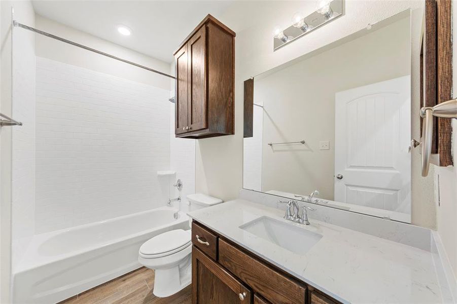 Full bathroom with wood-type flooring, vanity, toilet, and shower / washtub combination