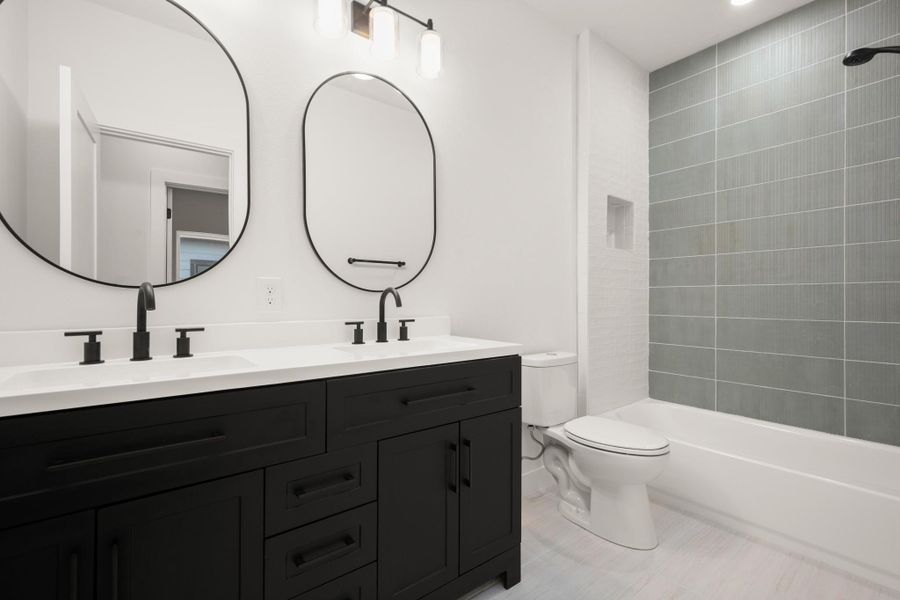 Full bathroom with double vanity and washtub / shower combination