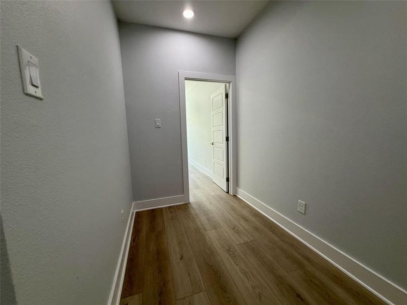Hallway featuring wood-finish flooring, light gray walls, white baseboards, and recessed lighting Hallway featuring wood-finish flooring, light gray walls, white baseboards, and recessed lighting