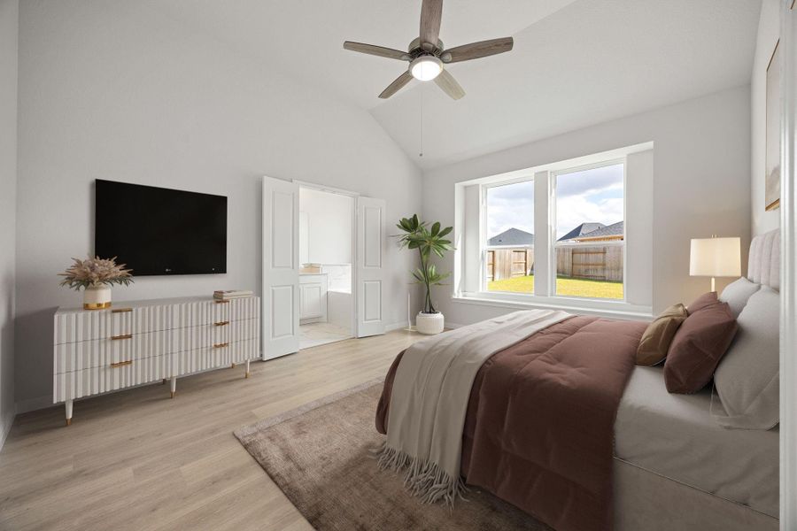 A serene and spacious primary bedroom retreat featuring an elegant vaulted ceiling and durable, wood-look flooring. Abundant natural light fills the space through a large double window. French doors open to the private en-suite bathroom. The room is completed by neutral gray walls, a modern ceiling fan, and plenty of space for a king-size bed and furniture. A serene and spacious primary bedroom retreat featuring an elegant vaulted ceiling and durable, wood-look flooring. Abundant natural light fills the space through a large double window. French doors open to the private en-suite bathroom. The room is completed by neutral gray walls, a modern ceiling fan, and plenty of space for a king-size bed and furniture.