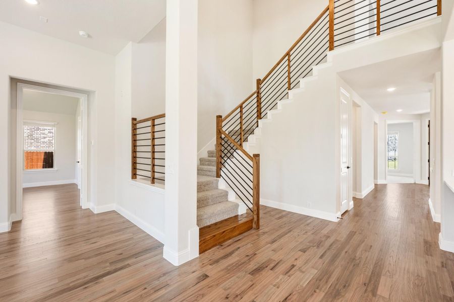 Open foyer with two-story staircase, wood and metal railing, and hardwood floors Open foyer with two-story staircase, wood and metal railing, and hardwood floors