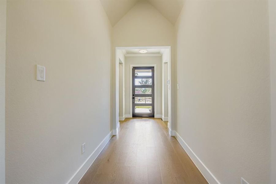 Hall featuring light wood-style flooring and lofted ceiling