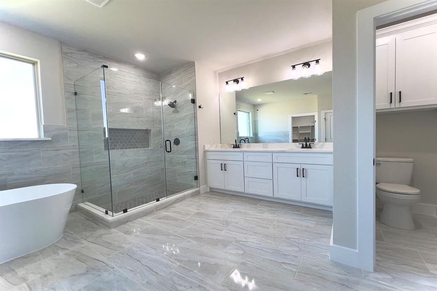 Full bath with double vanity, a freestanding tub, a stall shower, and tile finish flooring