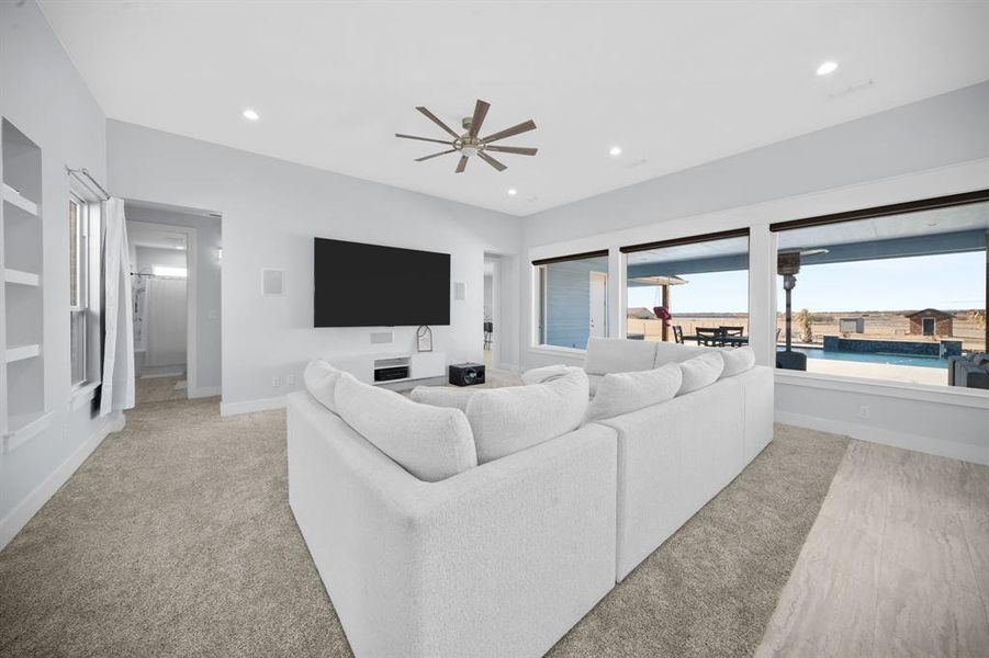 Living area with ceiling fan, light carpet, recessed lighting, and built in features