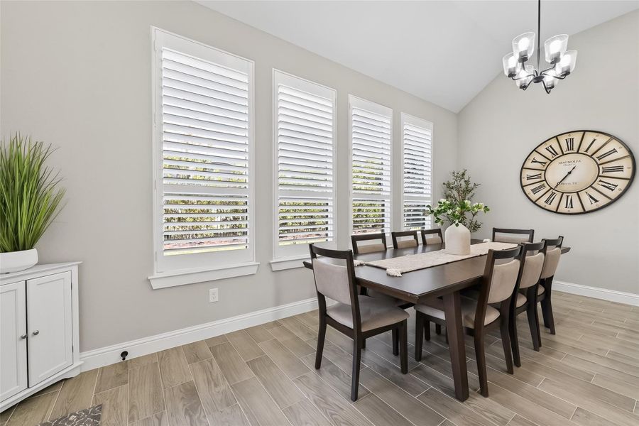 Formal dining area with large windows and elegant lighting. Formal dining area with large windows and elegant lighting.