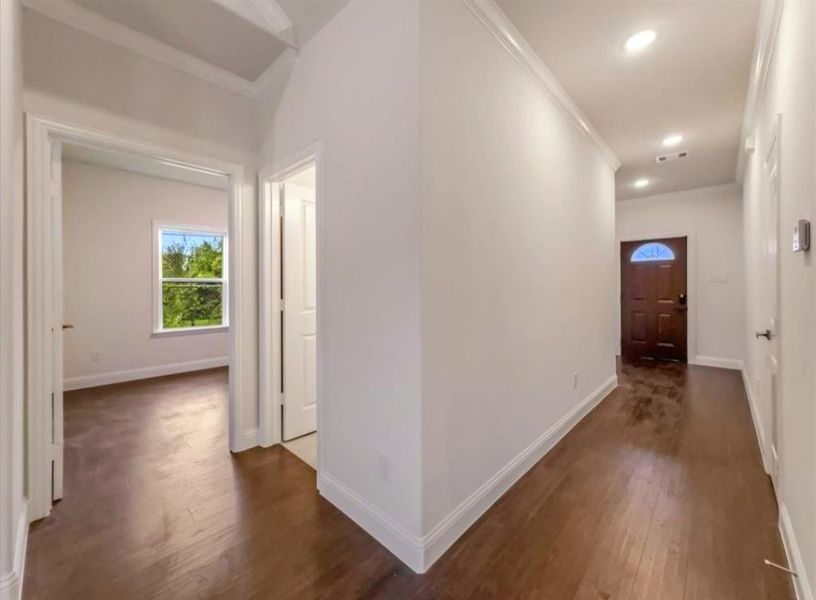 Hall featuring crown molding and dark wood-style flooring Hall featuring crown molding and dark wood-style flooring