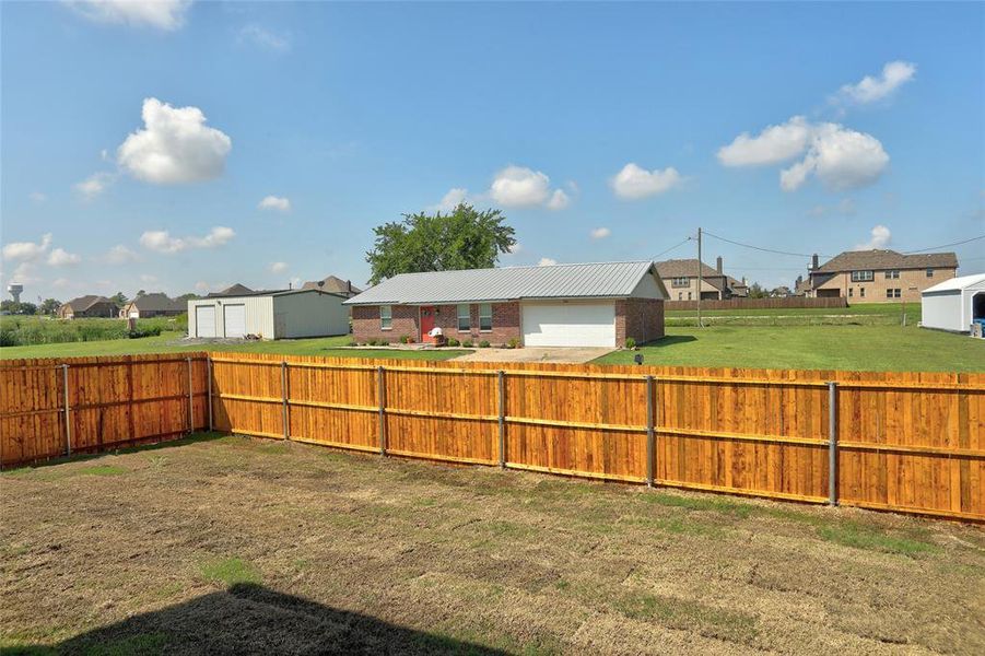 Fenced backyard featuring a residential view and a garage Fenced backyard featuring a residential view and a garage