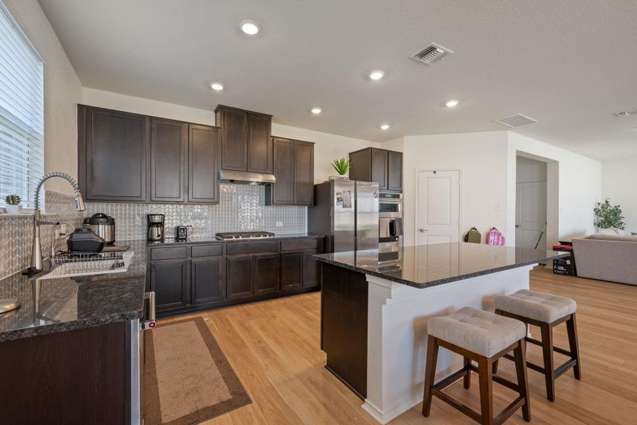 Kitchen featuring a breakfast bar area, dark wood finish cabinets, dark stone counters, light wood-type flooring, and a center island