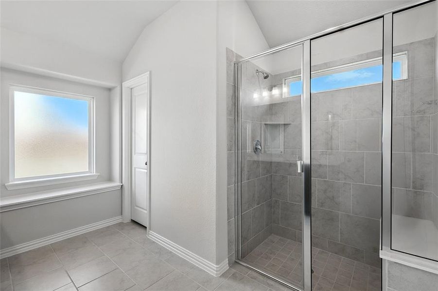 Full bath with healthy amount of natural light, lofted ceiling, a shower stall, and tile patterned floors Full bath with healthy amount of natural light, lofted ceiling, a shower stall, and tile patterned floors
