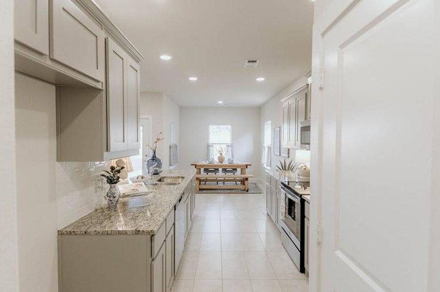 Kitchen with stainless steel appliances, light tile patterned floors, light stone counters, backsplash, and recessed lighting Kitchen with stainless steel appliances, light tile patterned floors, light stone counters, backsplash, and recessed lighting