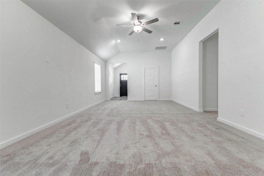 Another view of the living area highlights the impressive ceiling height, bright white walls, and open sightlines back toward the entry. The neutral carpet and clean finishes create a blank canvas, while the nearby openings provide convenient access to additional spaces throughout the home. Another view of the living area highlights the impressive ceiling height, bright white walls, and open sightlines back toward the entry. The neutral carpet and clean finishes create a blank canvas, while the nearby openings provide convenient access to additional spaces throughout the home.