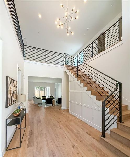 Stairway featuring wood finished floors, a chandelier, and a towering ceiling Stairway featuring wood finished floors, a chandelier, and a towering ceiling