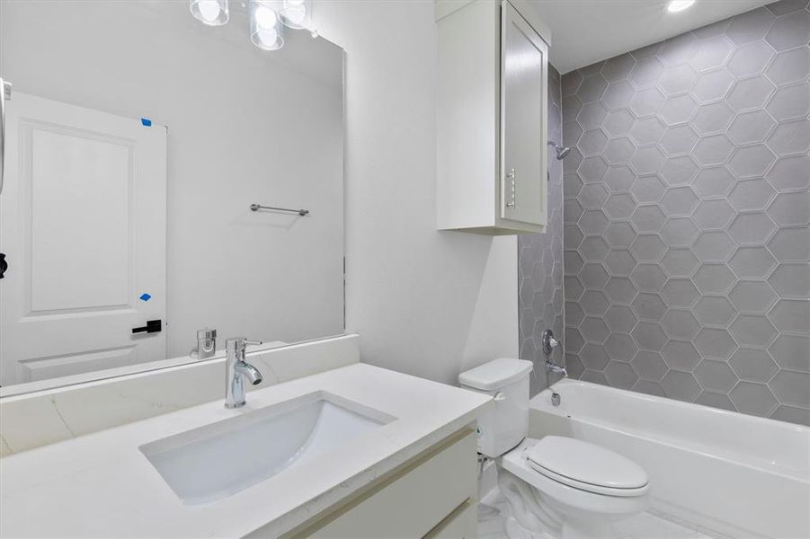 Full bathroom featuring tiled shower / bath combo, vanity, and toilet