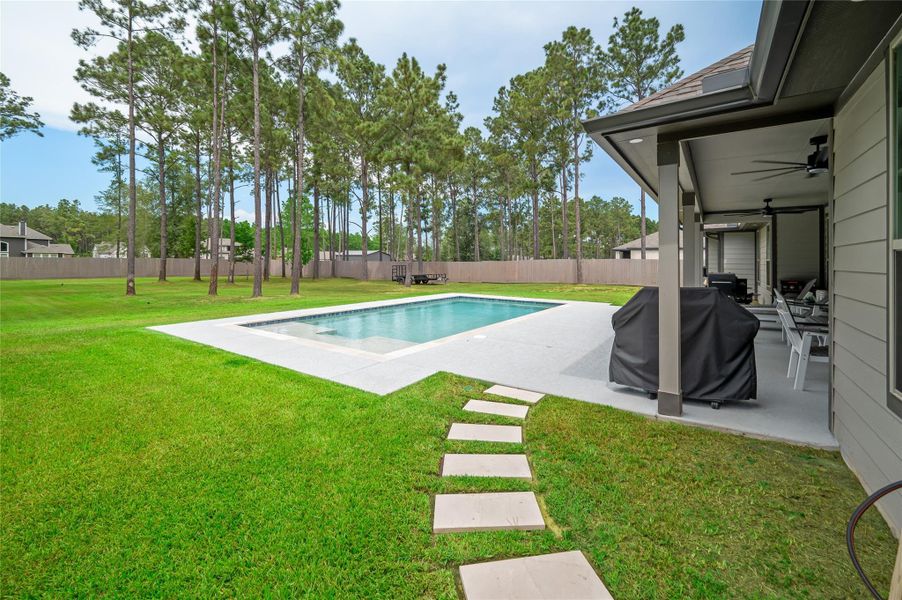 In-ground pool by a spacious backyard with mature trees and plenty of room to relax or entertain.