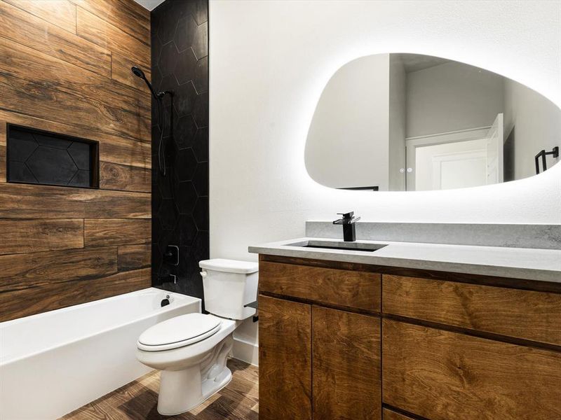 Bathroom featuring vanity, shower / tub combination, and dark wood finished floors Bathroom featuring vanity, shower / tub combination, and dark wood finished floors